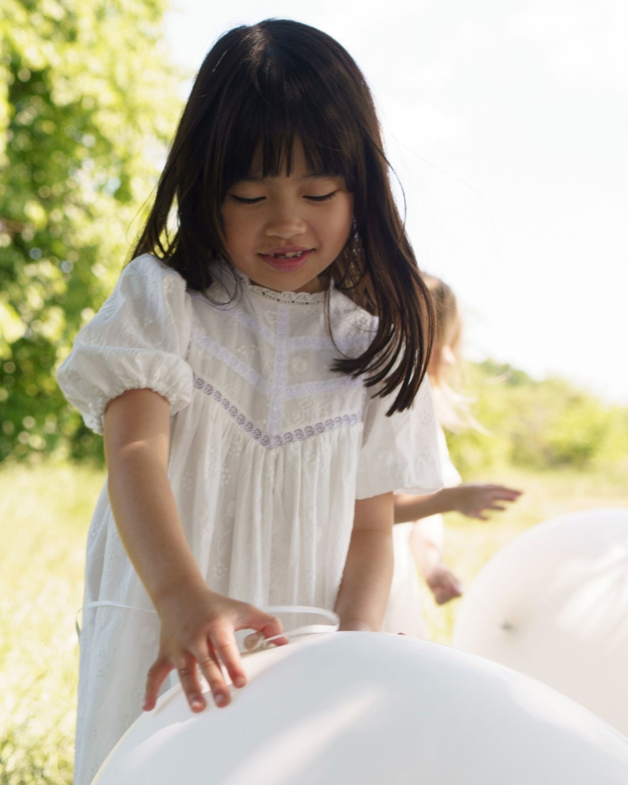 Early Sunday, Beth Dress in Ivory color, made from 100% cotton all over embroidered fabric, featuring Puff sleeves, contrast scalloped collar for a vintage touch, shown in a close up shot of model wearing it.