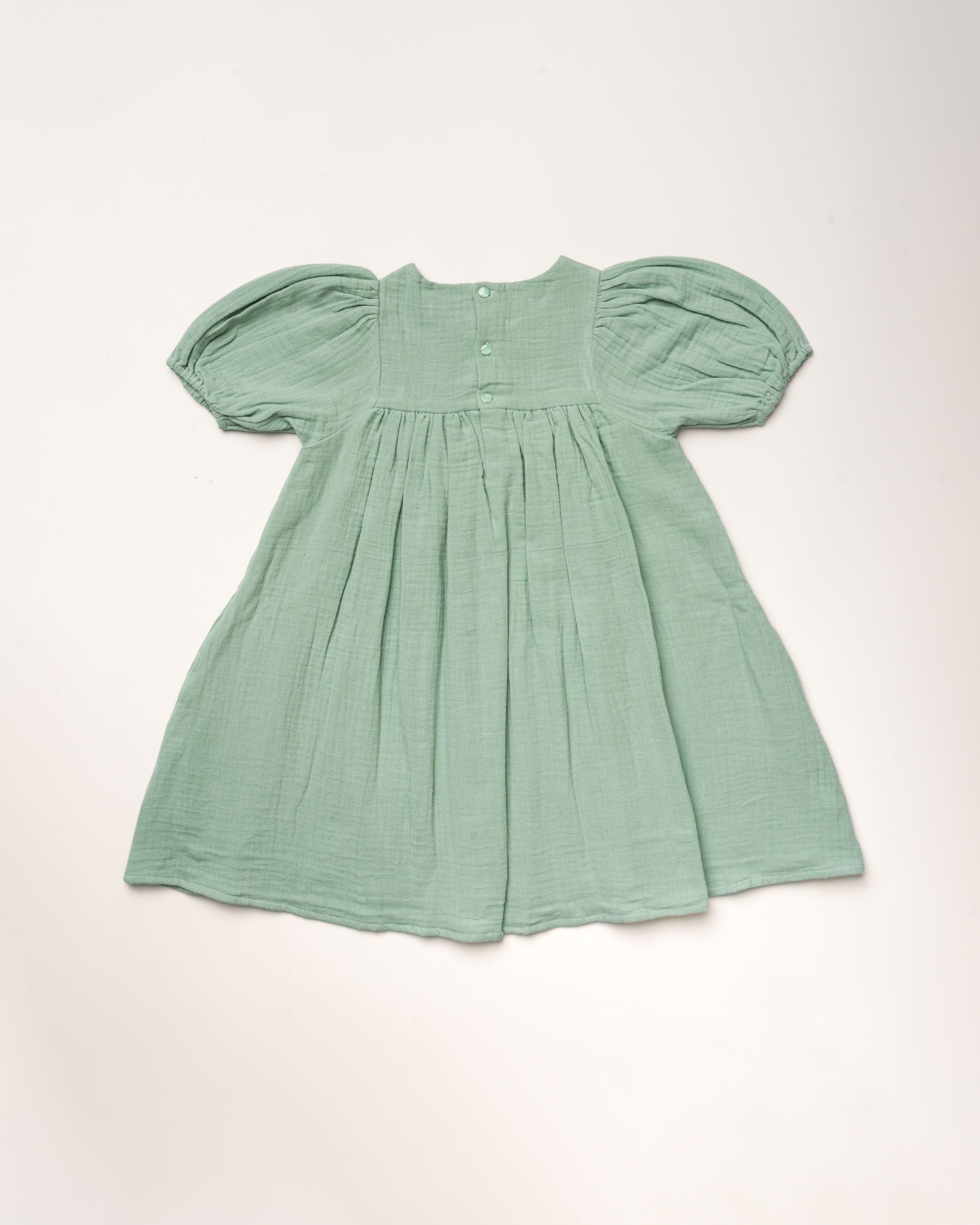 Early Sunday, Beth Dress in Mint color, made from 100% cotton double gauze solid fabric, featuring Puff sleeves, contrast scalloped collar for a vintage touch, shown in a back flat-lay view.