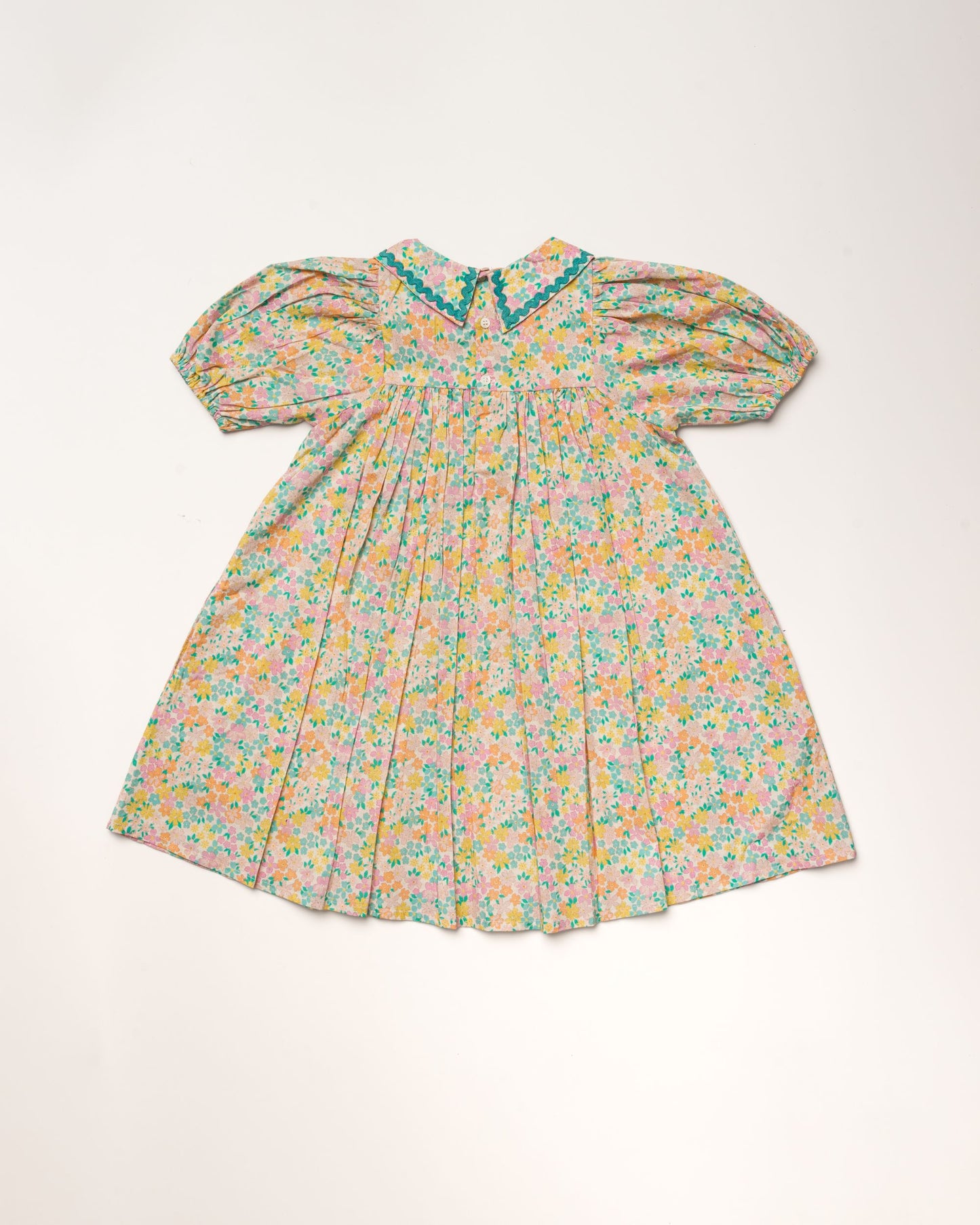 Early Sunday, Beth Dress in Emma Floral Mint color, made from printed cotton cambric fabric, featuring Puff sleeves, contrast scalloped collar for a vintage touch, shown in a back flat-lay view.