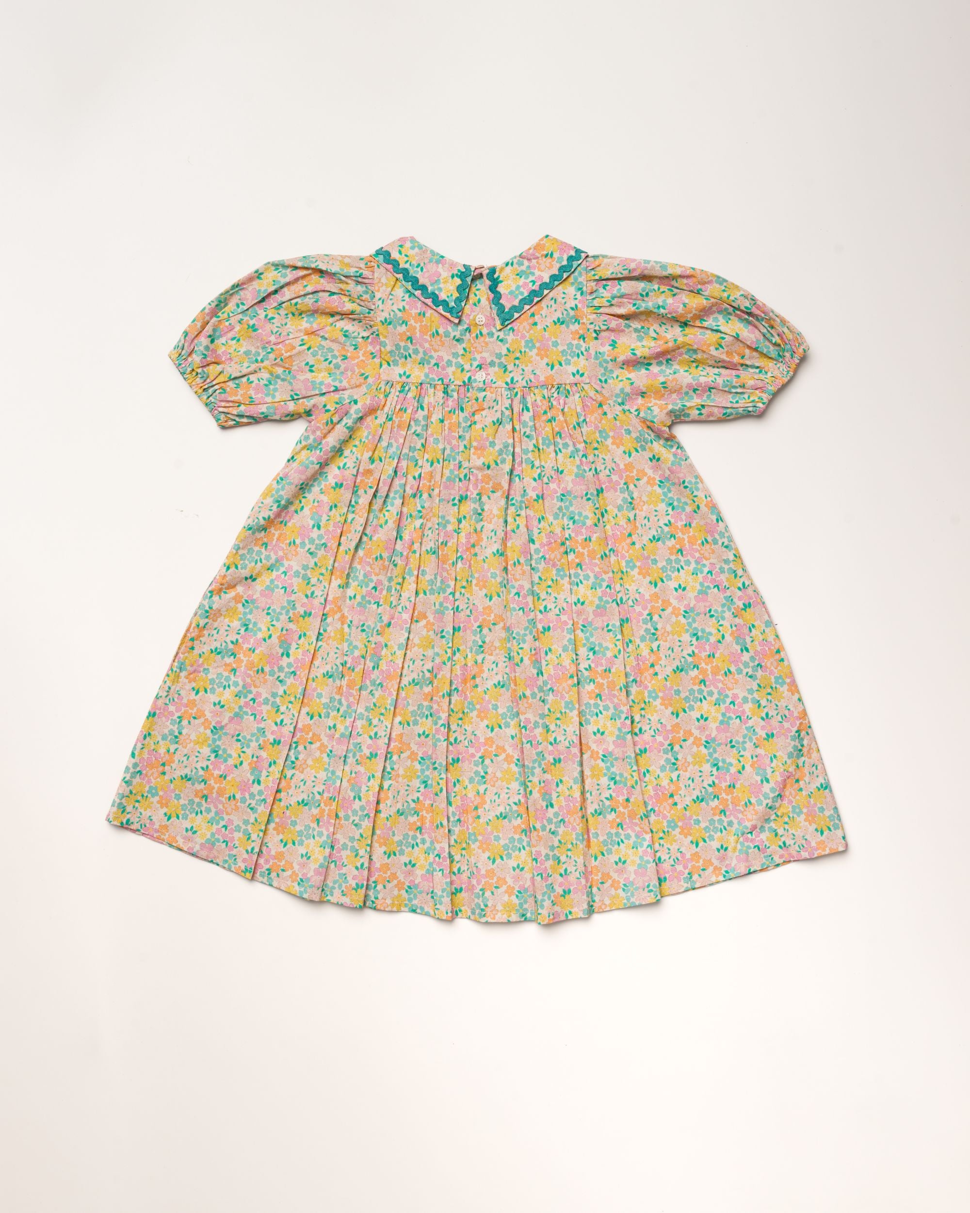 Early Sunday, Beth Dress in Emma Floral Mint color, made from printed cotton cambric fabric, featuring Puff sleeves, contrast scalloped collar for a vintage touch, shown in a back flat-lay view.