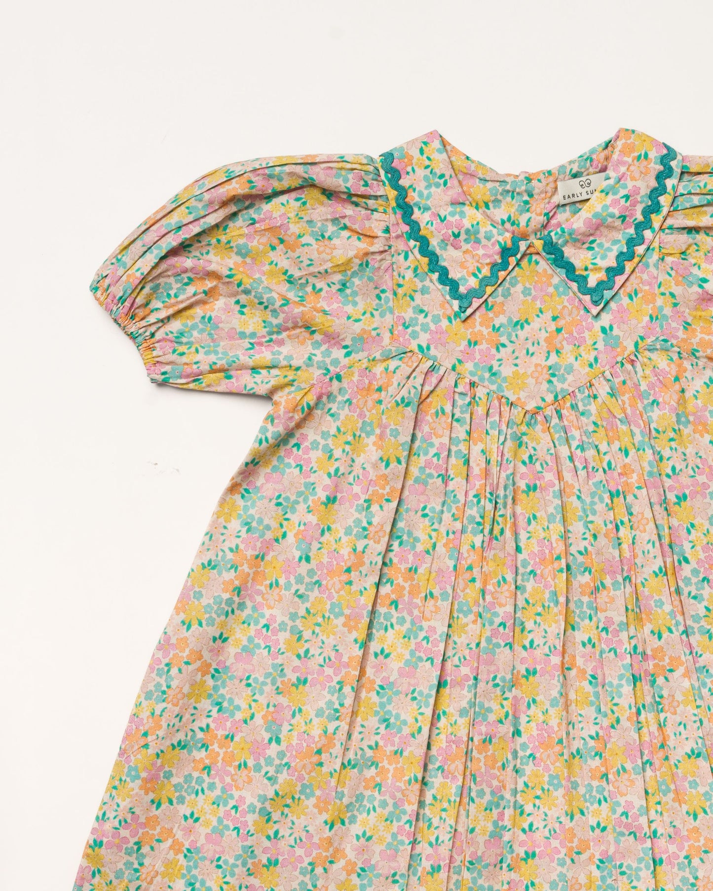 Early Sunday, Beth Dress in Emma Floral Mint color, made from printed cotton cambric fabric, featuring Puff sleeves, contrast scalloped collar for a vintage touch, shown in a closeup flat-lay view.