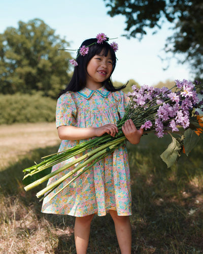 Early Sunday, Beth Dress in Emma Floral Mint color, made from printed cotton cambric fabric, featuring Puff sleeves, contrast scalloped collar for a vintage touch, shown in a model standing facing front wearing.