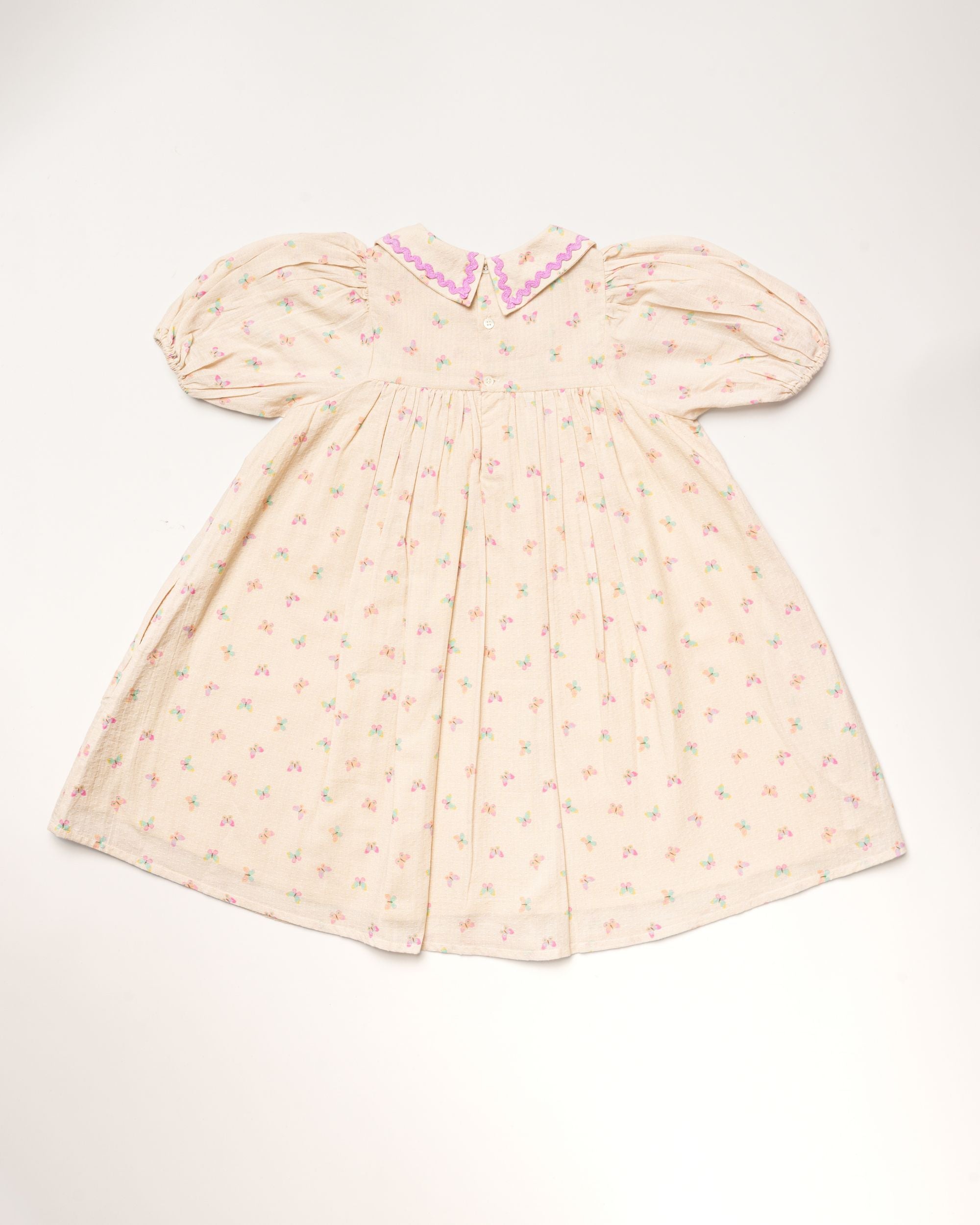 Early Sunday, Beth Dress in Butterfly Print color, made from printed cotton tiny swiss dobby fabric, featuring Puff sleeves, contrast scalloped collar for a vintage touch, shown in a back flat-lay view.