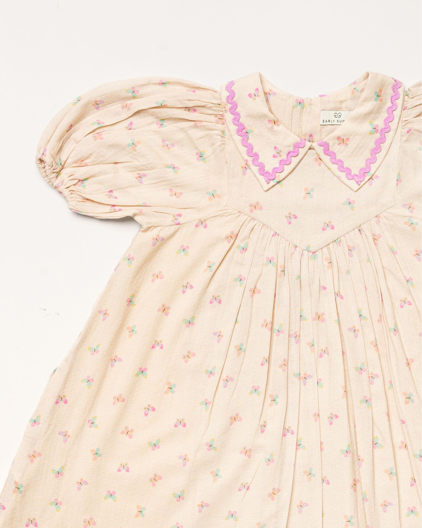 Early Sunday, Beth Dress in Butterfly Print color, made from printed cotton tiny swiss dobby fabric, featuring Puff sleeves, contrast scalloped collar for a vintage touch, shown in a closeup flat-lay view.