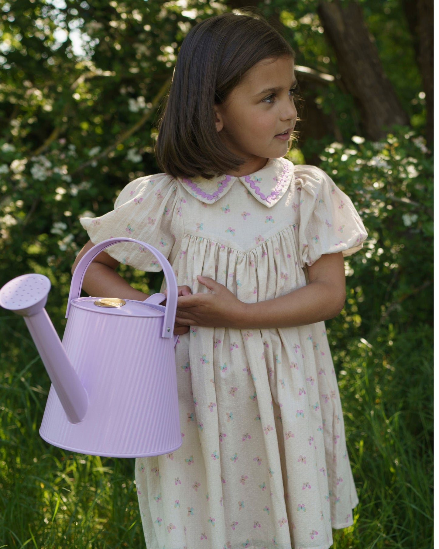 Early Sunday, Beth Dress in Butterfly Print color, made from printed cotton tiny swiss dobby fabric, featuring Puff sleeves, contrast scalloped collar for a vintage touch, shown in a model wearing outdoors.