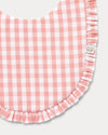 Early Sunday, Bib in Peony checks, made from Cotton Double Gauze fabric, shown in a closeup flat-lay view