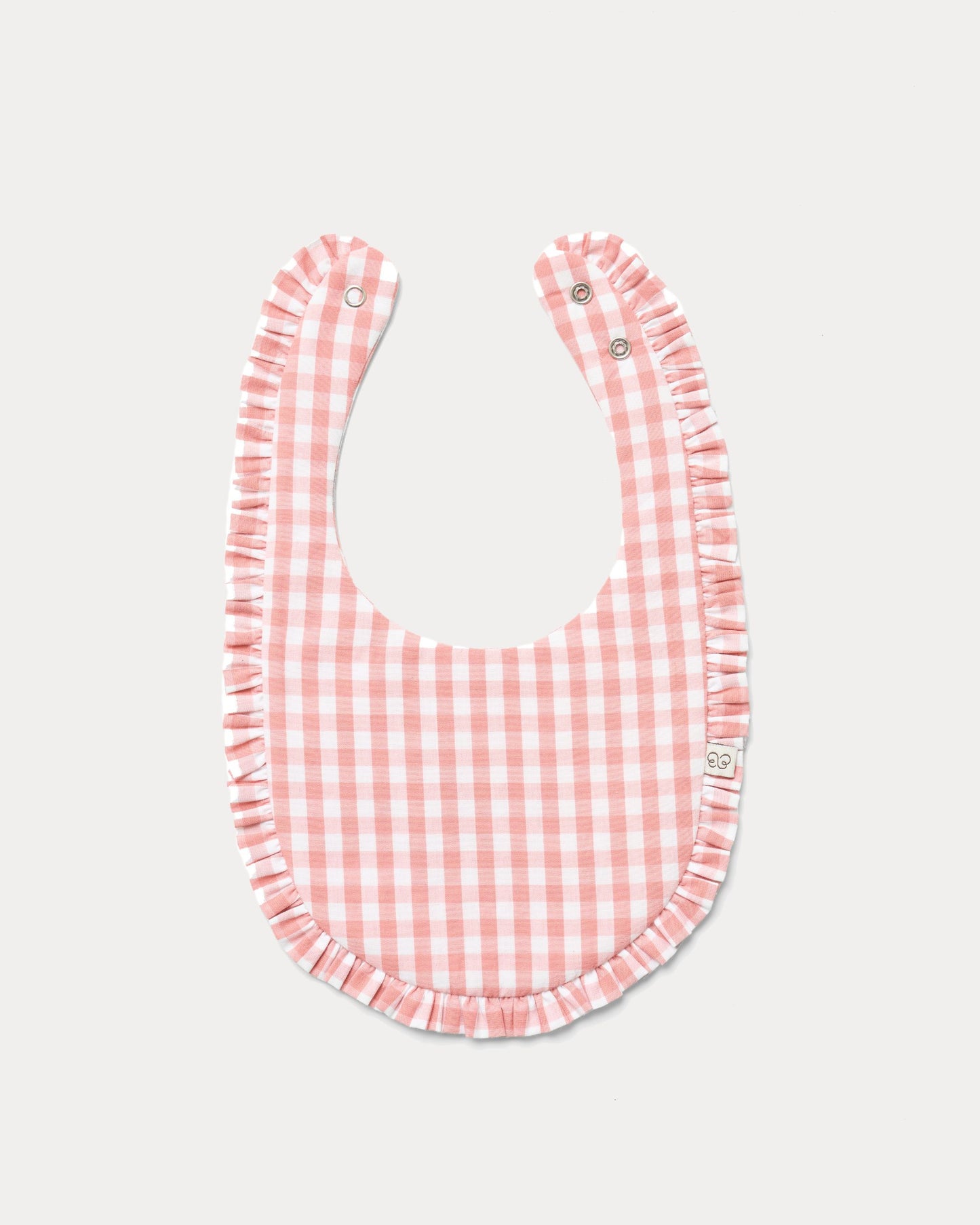 Early Sunday, Bib in Peony checks, made from Cotton Double Gauze fabric, shown in a front flat-lay view