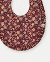Early Sunday, Bib in Garden Flowers Plum, made from Printed Cotton Satin fabric, featuring featuring a soft and comfortable design with an adjustable fit, shown in a closeup flat-lay view
