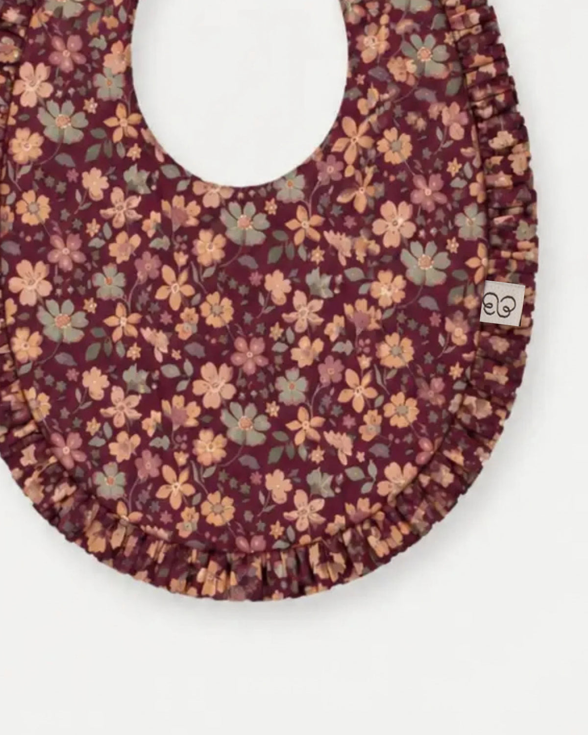 Early Sunday, Bib in Garden Flowers Plum, made from Printed Cotton Satin fabric, featuring featuring a soft and comfortable design with an adjustable fit, shown in a closeup flat-lay view
