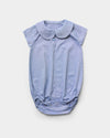 Early Sunday, Bobby Baby Romper in Summer Sky color, made from 100% Cotton Chambray fabric, featuring short sleeves with peter pan collar, shown in a front flat-lay view