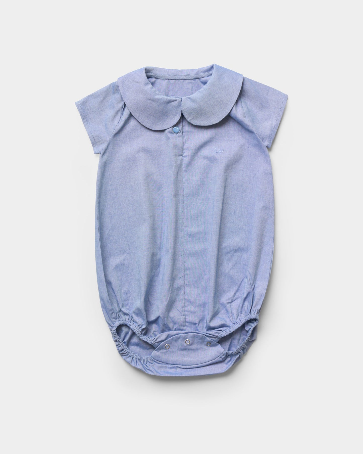 Early Sunday, Bobby Baby Romper in Summer Sky color, made from 100% Cotton Chambray fabric, featuring short sleeves with peter pan collar, shown in a front flat-lay view