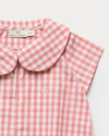 Early Sunday, Bobby Baby Romper in Peony color, made from 100% Cotton Gingham Check fabric, featuring short sleeves with peter pan collar, shown in a closeup flat-lay view