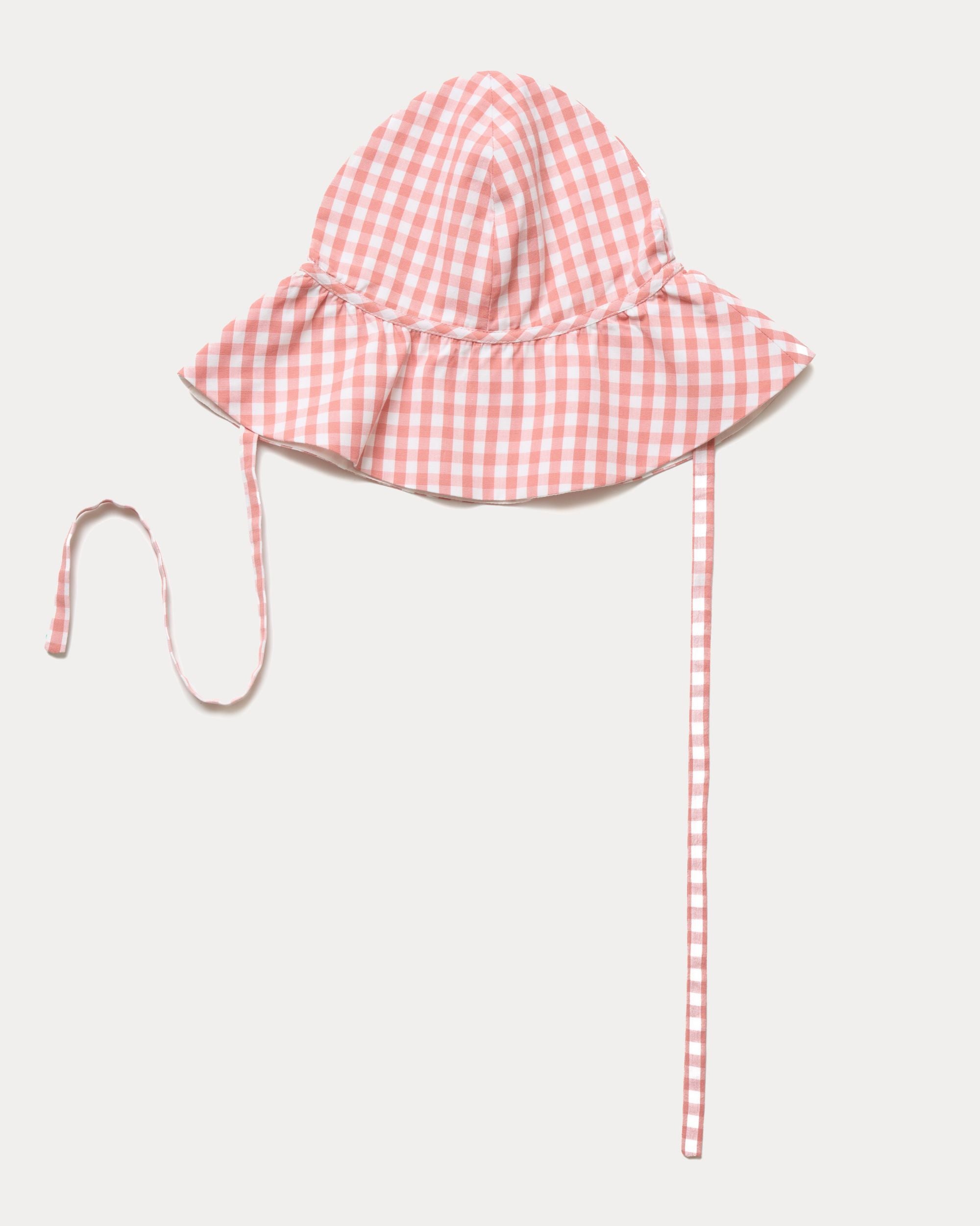 Early Sunday, Bonnie Hat Cap in Peony color, made from Gingham Check fabric, shown in an angled view with wide brim and tie straps