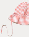 Early Sunday, Bonnie Hat Cap in Peony color, made from Gingham Check fabric, shown in a closeup flat-lay view