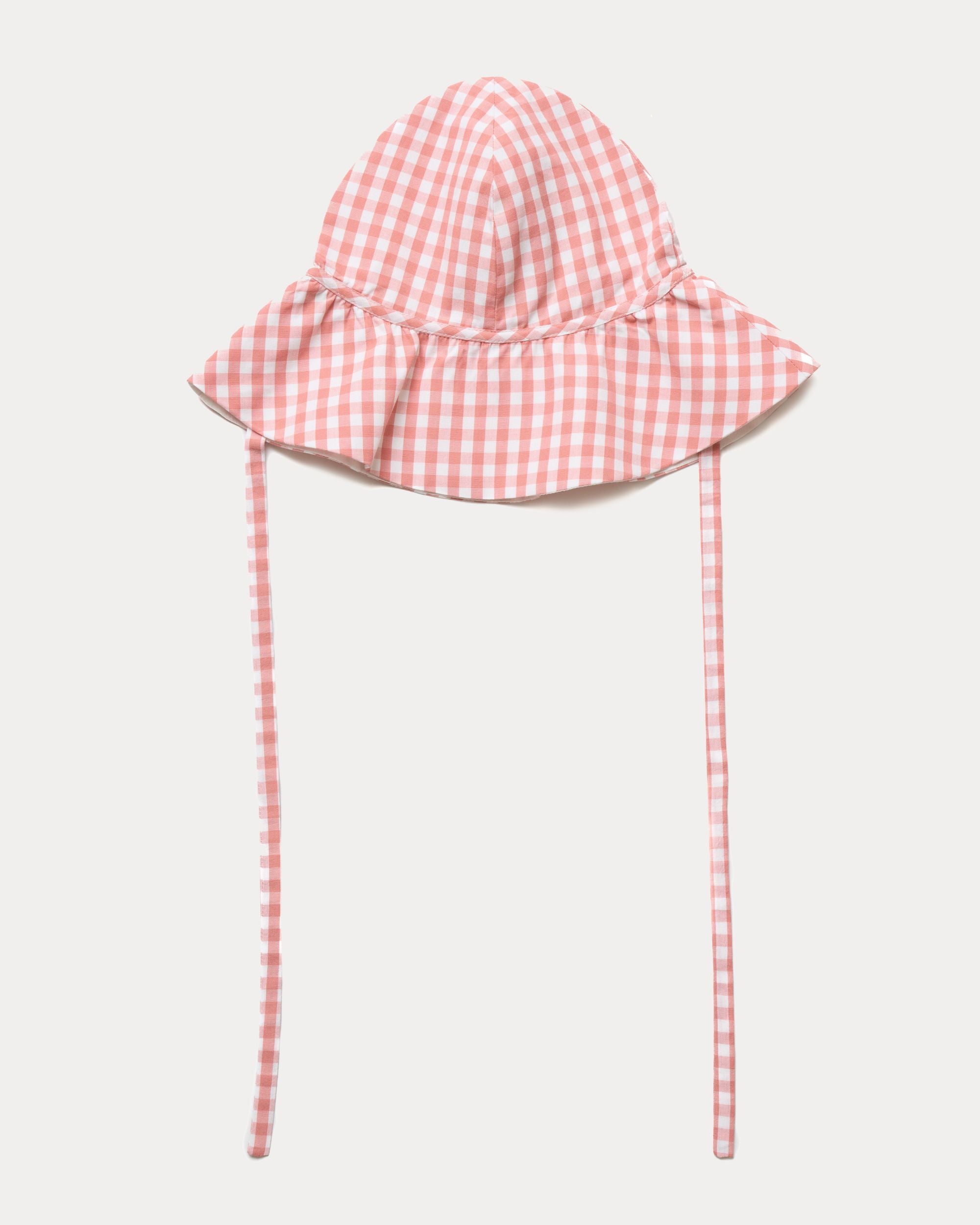 Early Sunday, Bonnie Hat Cap in Peony color, made from Gingham Check fabric, shown in a front flat-lay view with wide brim and tie straps