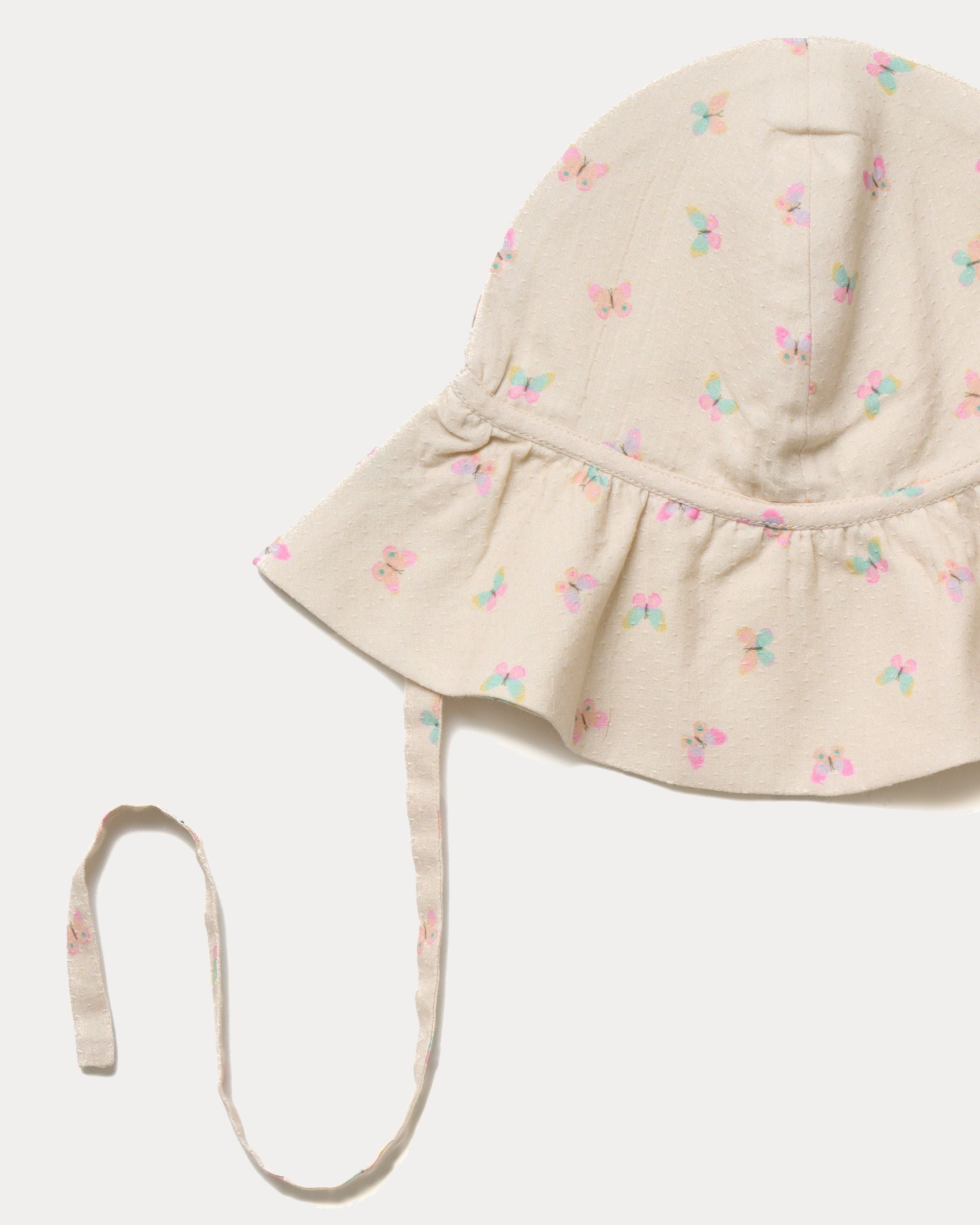 Early Sunday, Bonnie Hat Cap in Butterflies print, made from Printed Tiny Swiss Dobby fabric, shown in a closeup flat-lay view