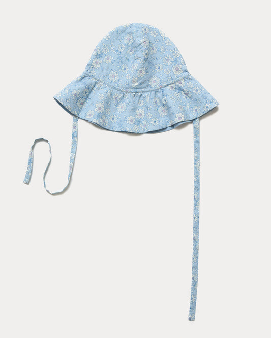 Early Sunday, Bonnie Hat Cap in Tonal Floral Blue color, made from Printed Tiny Swiss Dobby fabric, shown in an angled view with wide brim and tie straps
