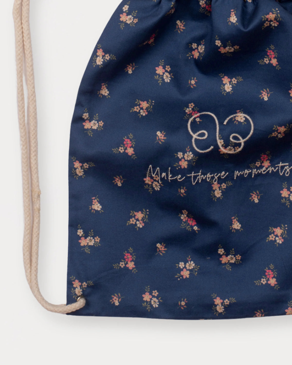 Early Sunday, Bunny Bag in Ditsy Bouquet Navy Blue, made from Printed Cotton Satin fabric, featuring a bunny-ear design with a drawstring closure, shown in a closeup flat-lay view