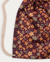 Early Sunday, Bunny Bag in Garden Flowers Plum, made from Printed Cotton Satin fabric, featuring a bunny-ear design with a drawstring closure, shown in a closeup flat-lay view
