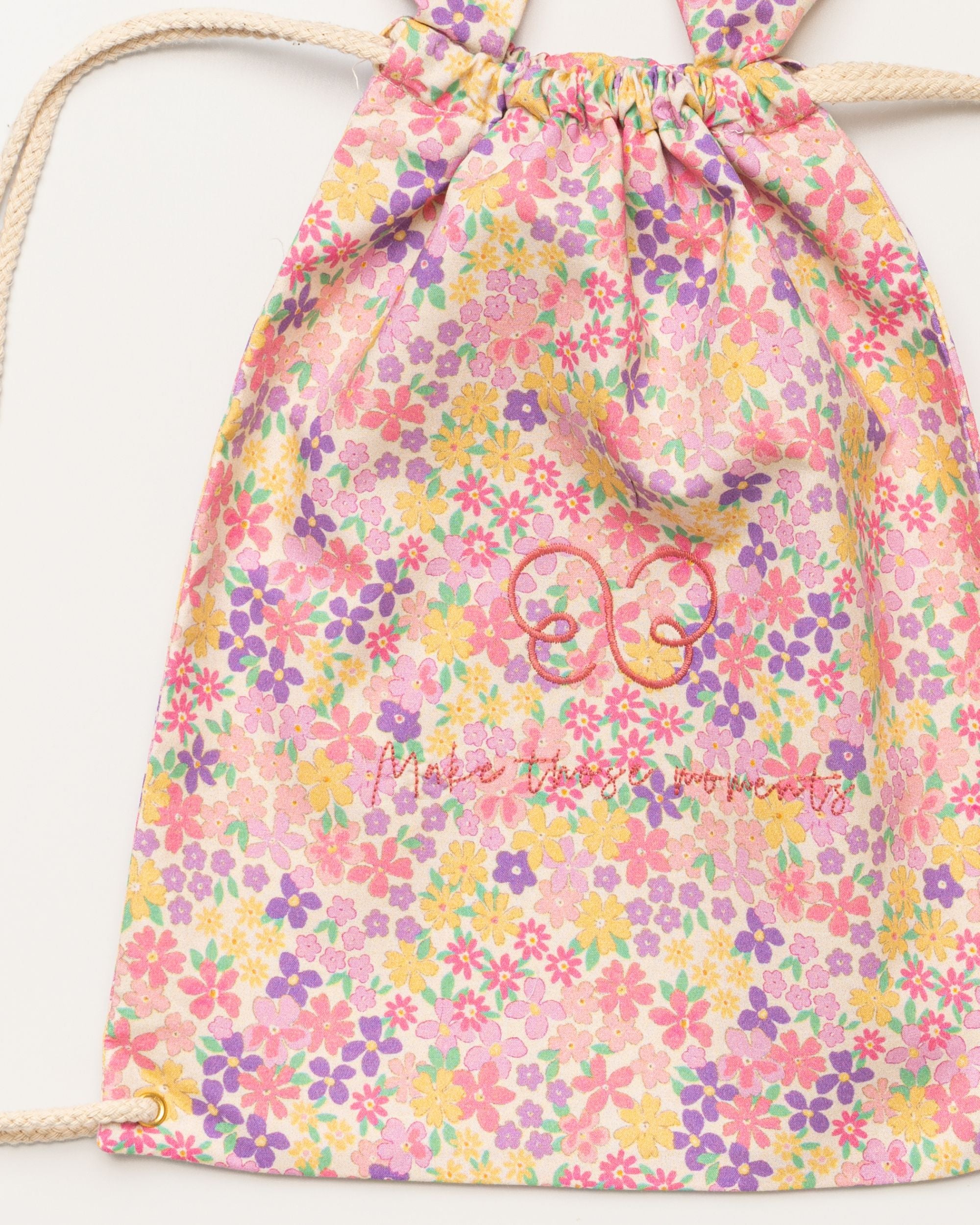 Early Sunday, Bunny Drawstring Backpack in Emma Floral Purple color, made from Organic Printed Cotton Cambric fabric, featuring a bunny-ear design with a drawstring closure, shown in a closeup flat-lay view