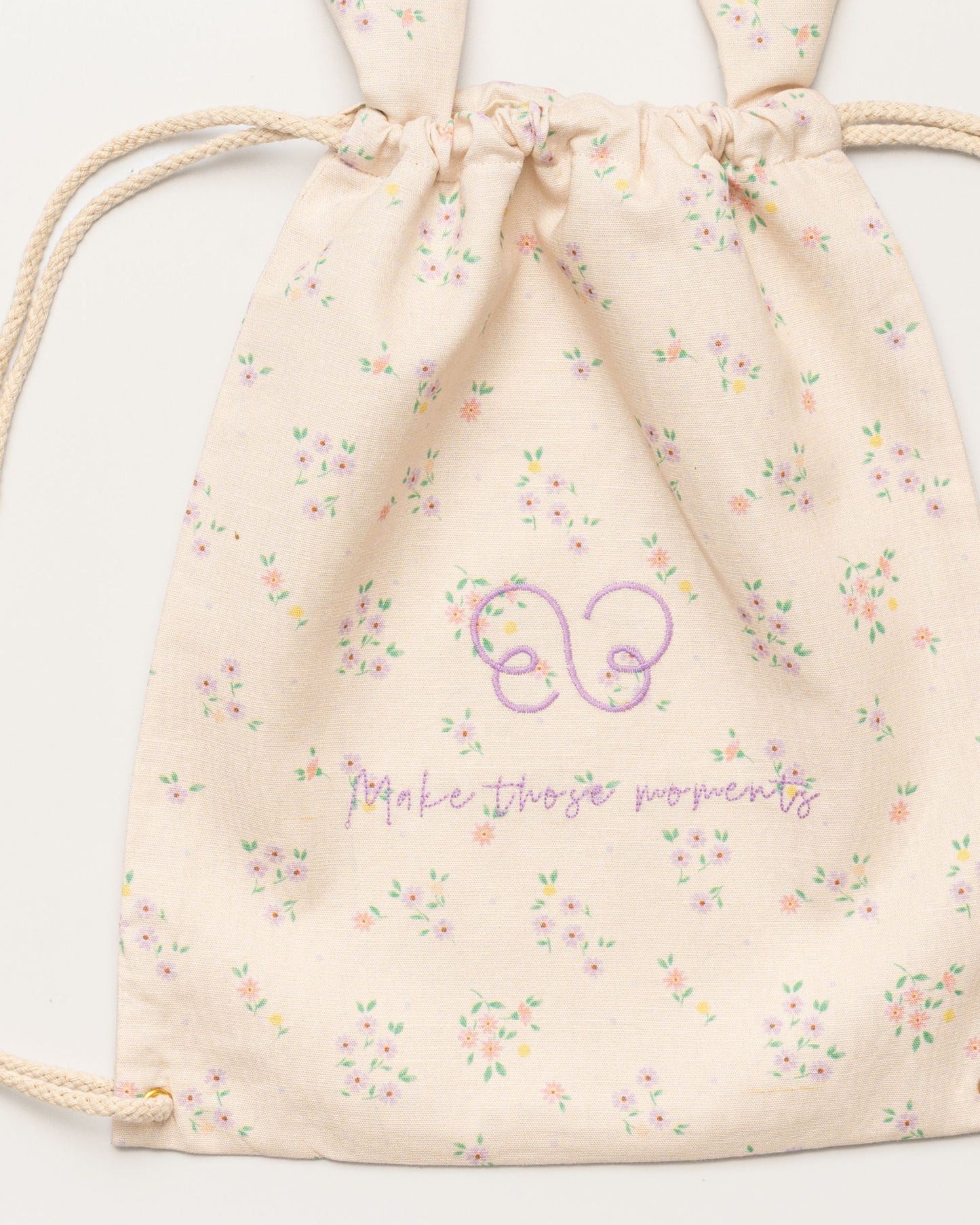 Early Sunday, Bunny Drawstring Backpack in Painted Bouquet print, made from Printed 70% Cotton, 30% Linen fabric, featuring a bunny-ear design with a drawstring closure, shown in a closeup flat-lay view