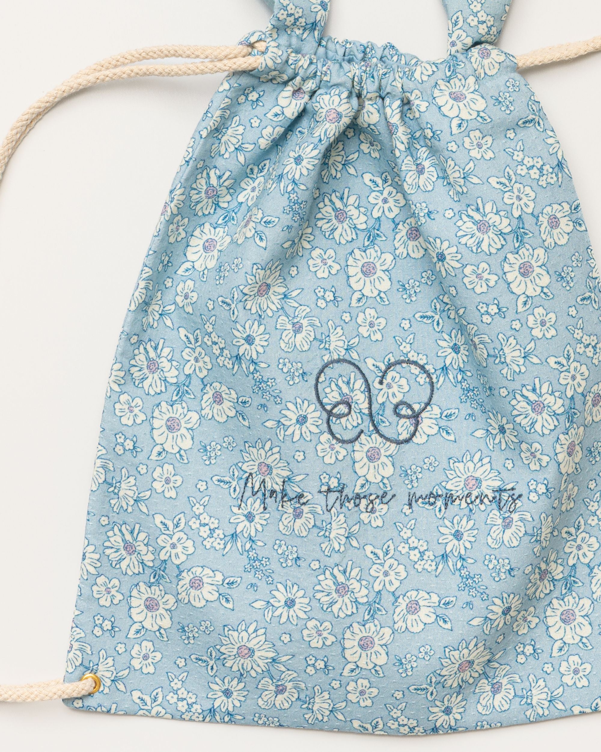 Early Sunday, Bunny Drawstring Backpack in Tonal Floral Blue color, made from Printed Cotton Tiny Swiss Dobby fabric, featuring a bunny-ear design with a drawstring closure, shown in a closeup flat-lay view