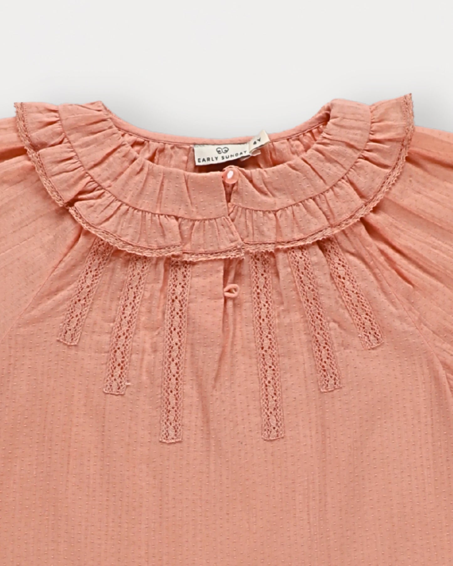Early Sunday, Cécile Blouse in Blush, made from Cotton Swiss Dobby fabric, featuring a relaxed silhouette with gathered sleeves and delicate detailing, shown in a closeup flat-lay view