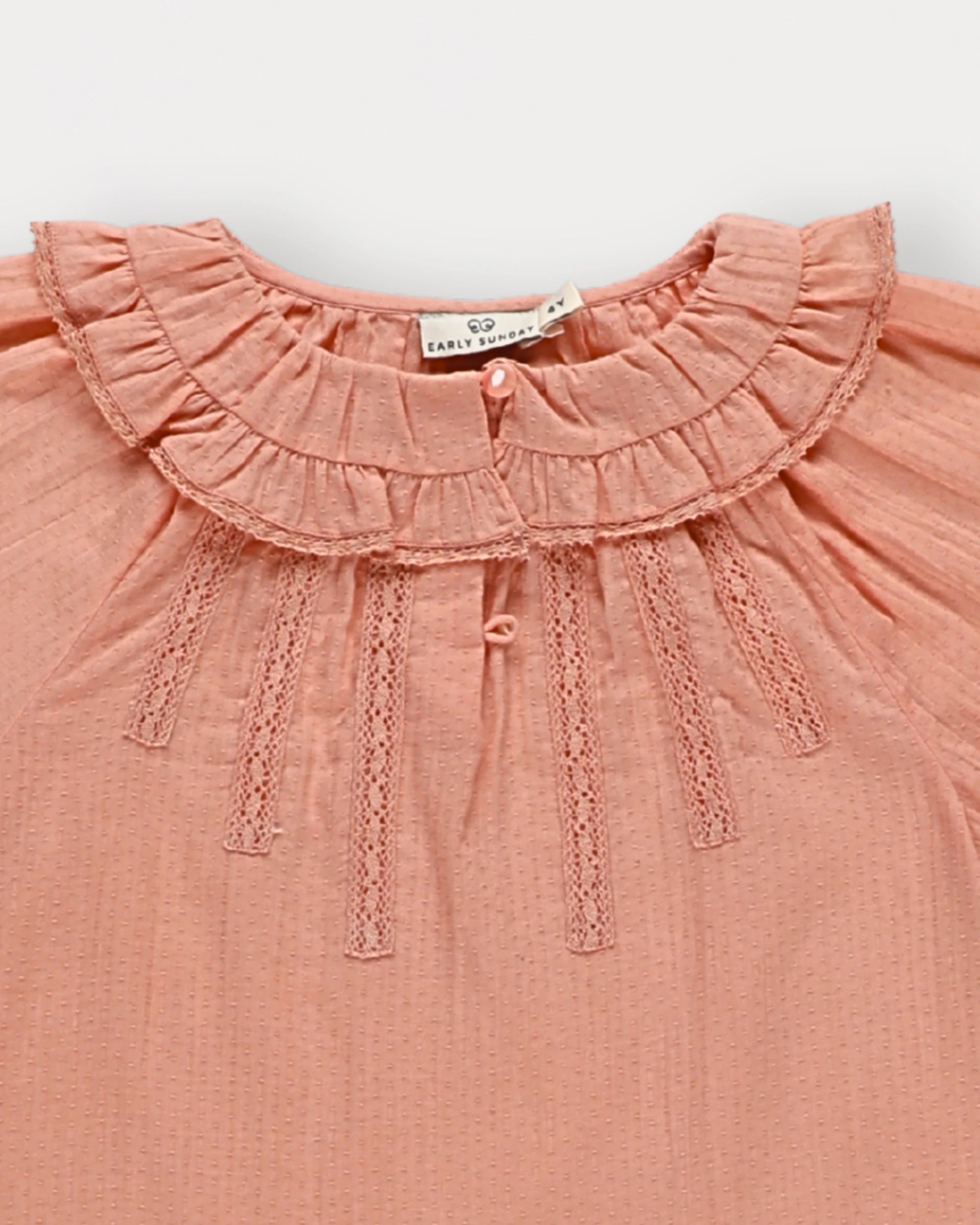 Early Sunday, Cécile Blouse in Blush, made from Cotton Swiss Dobby fabric, featuring a relaxed silhouette with gathered sleeves and delicate detailing, shown in a closeup flat-lay view