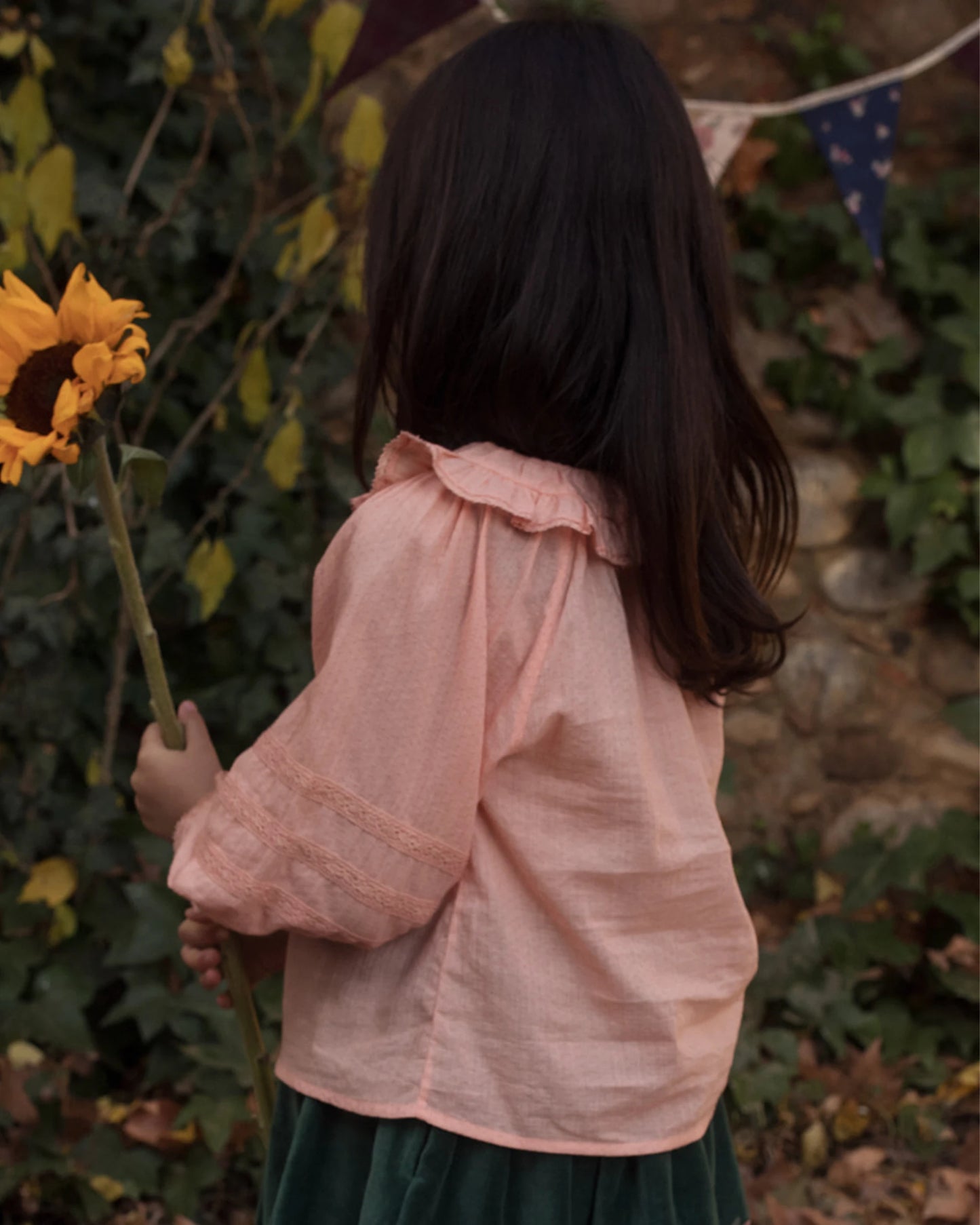 Early Sunday, Cécile Blouse in Blush, made from Cotton Swiss Dobby fabric, featuring a relaxed silhouette with gathered sleeves and delicate detailing, shown in a side view of model wearing outdoors