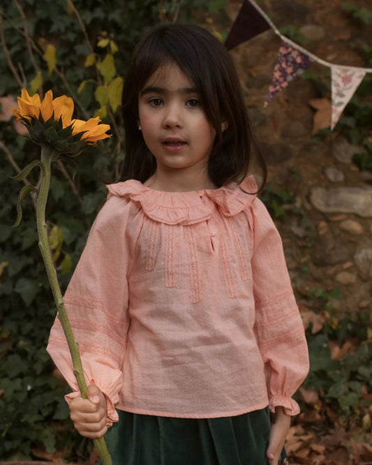 Early Sunday, Cécile Blouse in Blush, made from Cotton Swiss Dobby fabric, featuring a relaxed silhouette with gathered sleeves and delicate detailing, shown in a front view of model playing outdoors
