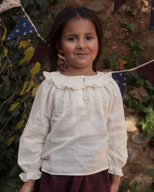 Early Sunday, Cécile Blouse in Ecru, made from Cotton Swiss Dobby fabric, featuring a relaxed silhouette with gathered sleeves and delicate detailing, shown in a front view of model wearing outdoors