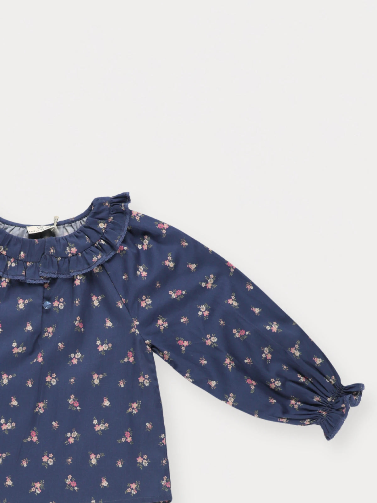 Early Sunday, Cécile Blouse in Ditsy Bouquet Navy, made from Printed Cotton Satin fabric, featuring a relaxed silhouette with gathered sleeves and delicate detailing, shown in a closeup flat-lay view