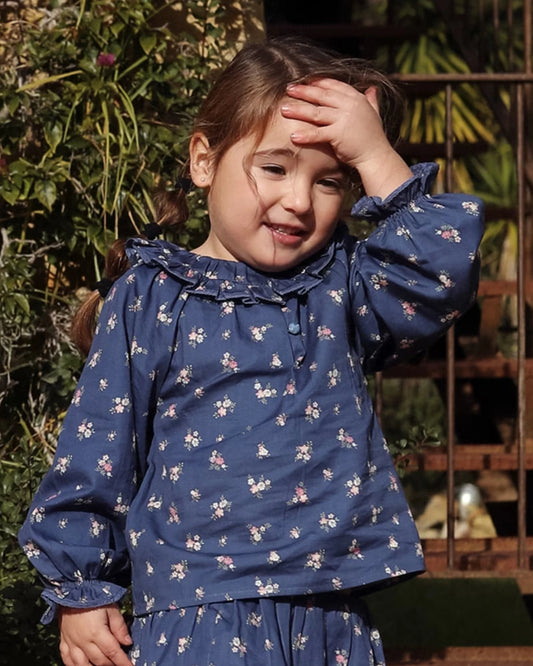 Early Sunday, Cécile Blouse in Ditsy Bouquet Navy, made from Printed Cotton Satin fabric, featuring a relaxed silhouette with gathered sleeves and delicate detailing, shown in a front view of model wearing outdoors