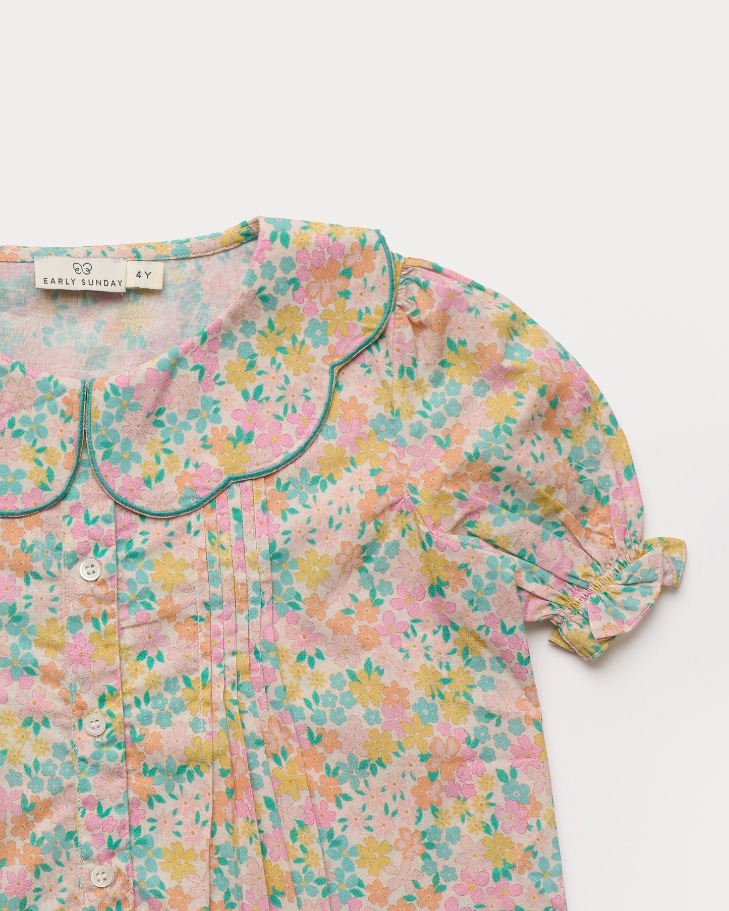 Early Sunday, Camelia Blouse in Emma Floral Mint color, made from printed 60s cotton cambric fabric, featuring short sleeves with peter pan collar, shown in a closeup flat-lay view