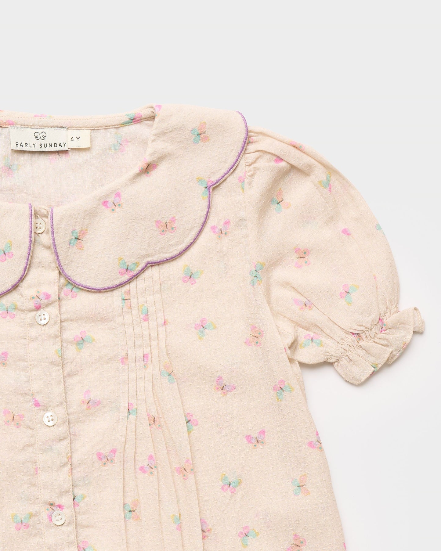 Early Sunday, Camelia Blouse in Butterfly Print color, made from printed cotton tiny swiss dobby fabric, featuring short sleeves with peter pan collar, shown in a closeup flat-lay view