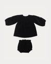 Early Sunday, Cara Baby Dress & Bloomer Set in Black, made from Cotton Velvet Velour's fabric, featuring a floral embroidery around the neckline with matching bloomer, shown in a back flat-lay view