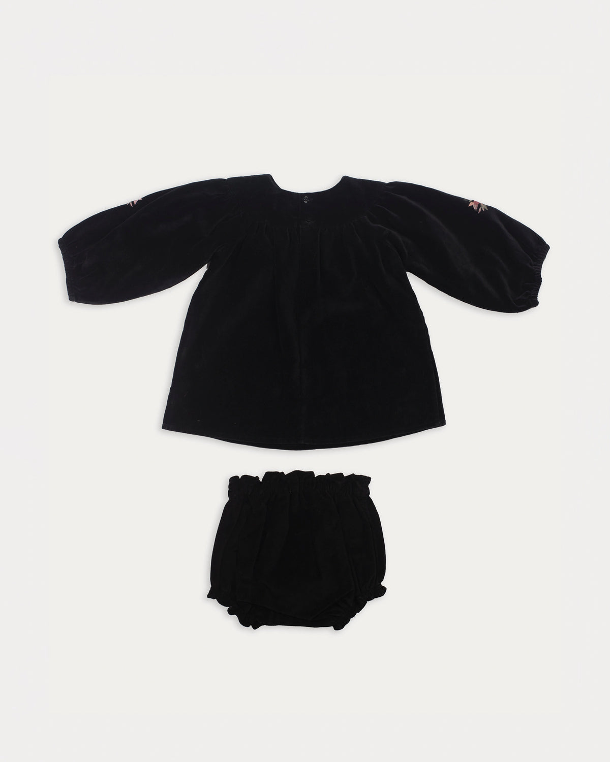 Early Sunday, Cara Baby Dress & Bloomer Set in Black, made from Cotton Velvet Velour's fabric, featuring a floral embroidery around the neckline with matching bloomer, shown in a back flat-lay view
