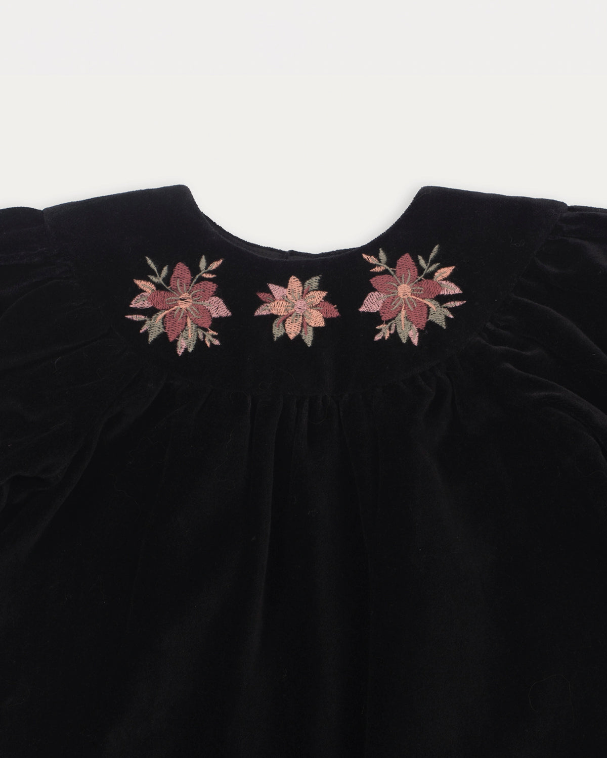 Early Sunday, Cara Baby Dress & Bloomer Set in Black, made from Cotton Velvet Velour's fabric, featuring a floral embroidery around the neckline, shown in a closeup flat-lay view