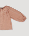 Early Sunday, Cecilia Blouse in Earthy Pink color, made from Cotton Swiss Dobby fabric, featuring relaxed fit, frill neckline, long sleeves with elasticated cuffs, and MOP buttons, shown in a closeup flat-lay view
