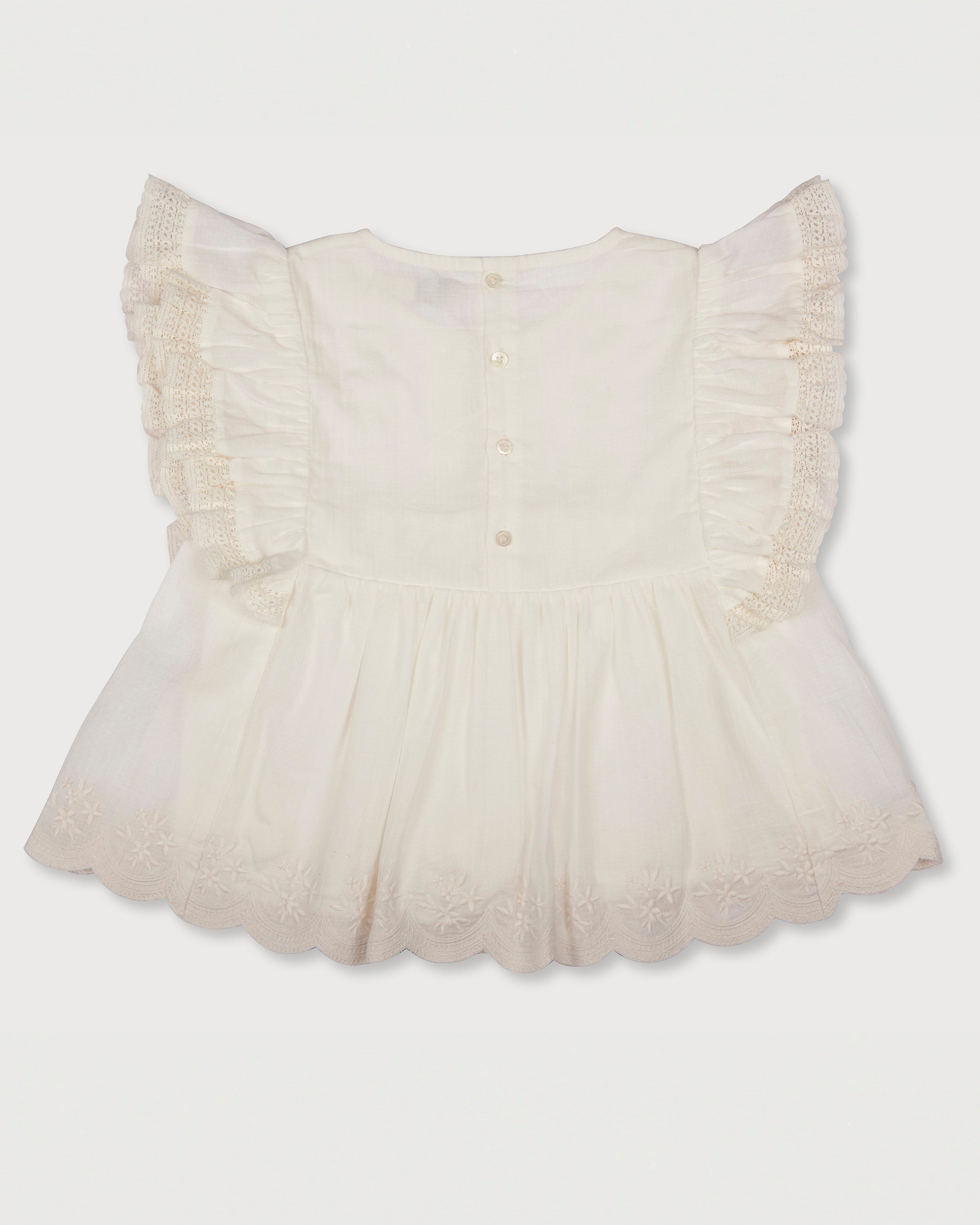 Early Sunday, Charlie Blouse in Ivory print, made from Cotton Tiny Swiss Dots fabric, featuring Flutter sleeves, pintuck detailing, and a flowy, gathered silhouette, shown in a back flat-lay view