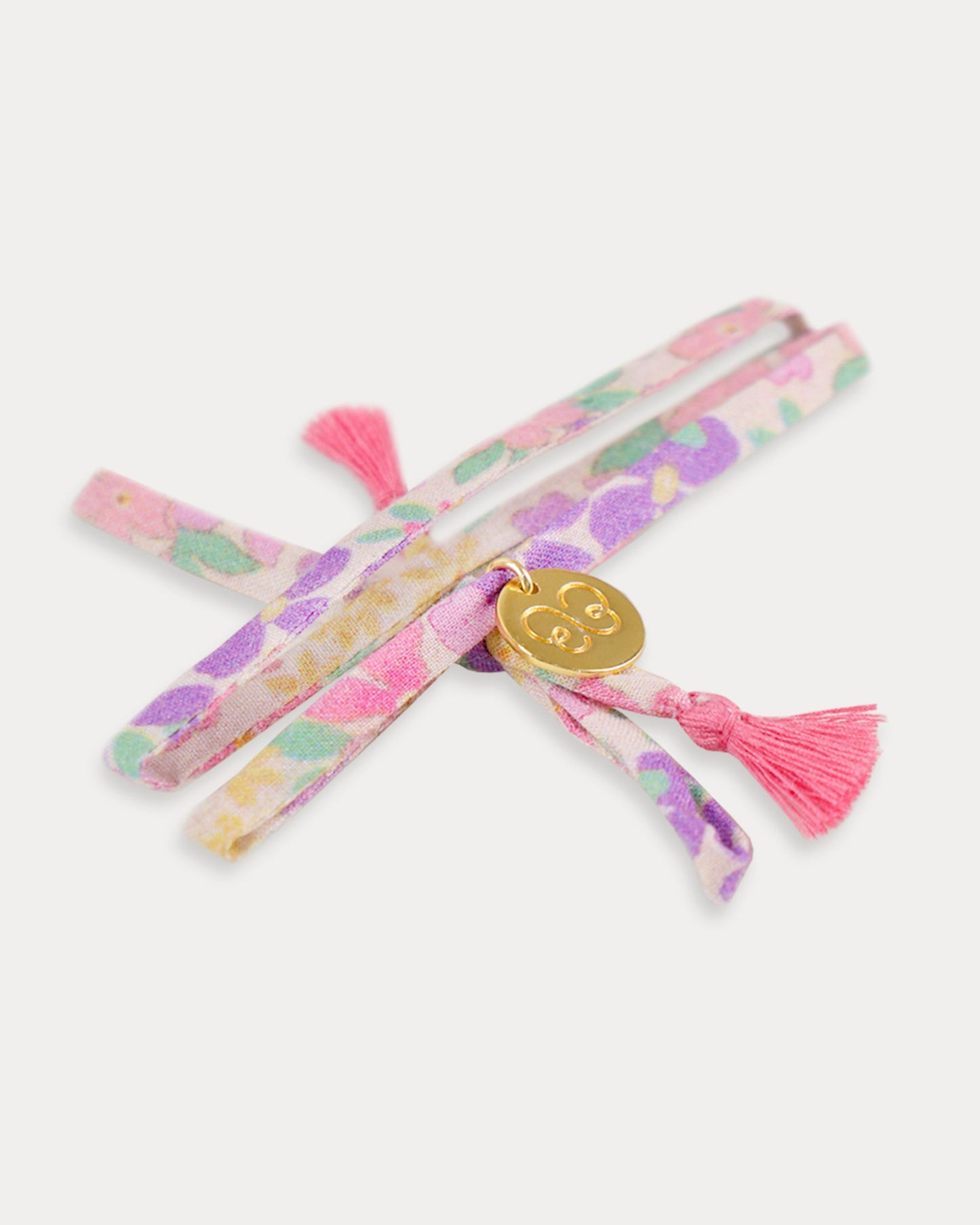 Early Sunday, Charm Bracelet in Emma Floral Purple color, made from Organic Printed Cotton Cambric fabric, featuring a soft fabric bracelet design with a charm, shown in an angled view with a close-up shot