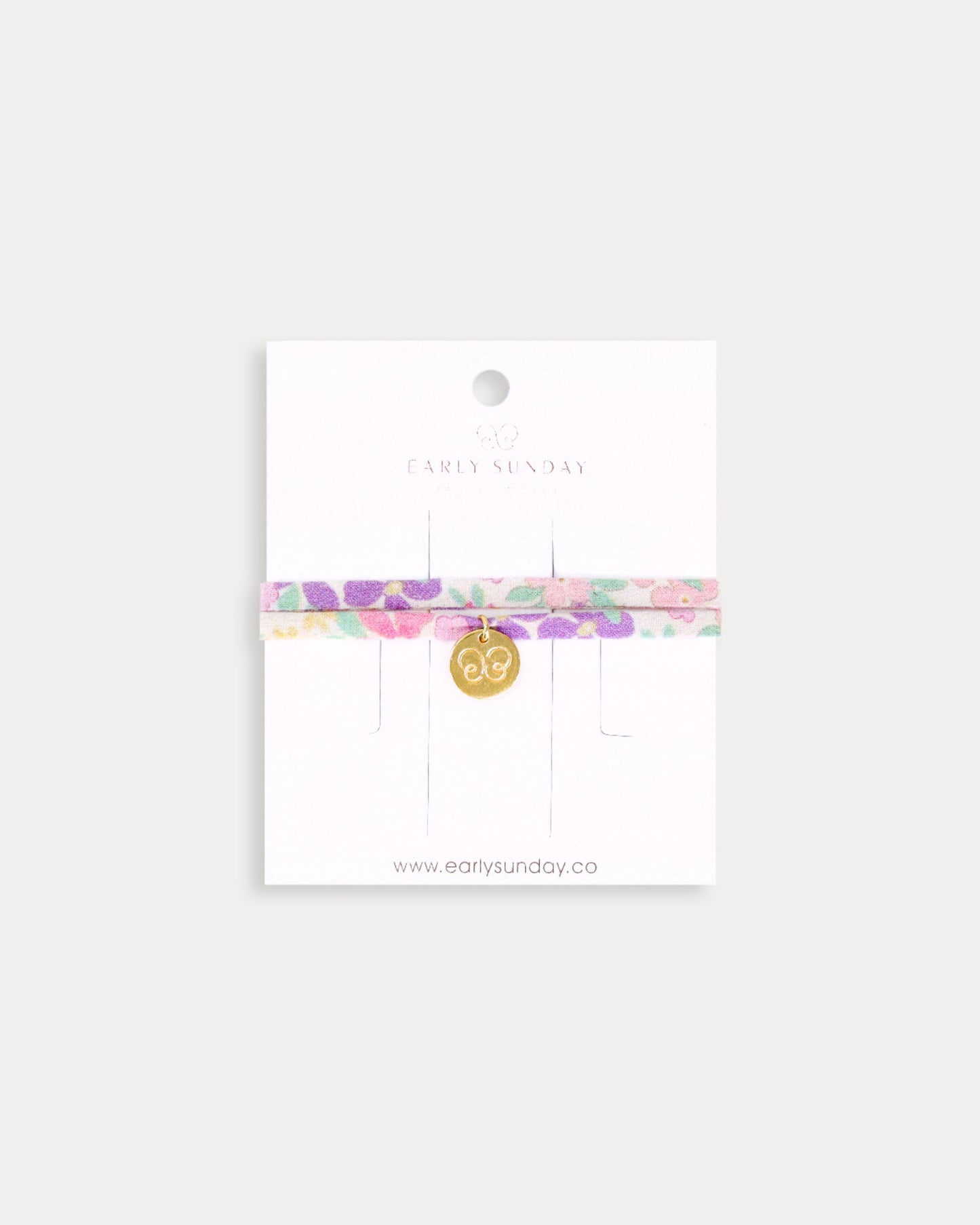 Early Sunday, Charm Bracelet in Emma Floral Purple color, made from Organic Printed Cotton Cambric fabric, featuring a soft fabric bracelet design with a charm, shown in a front flat-lay view