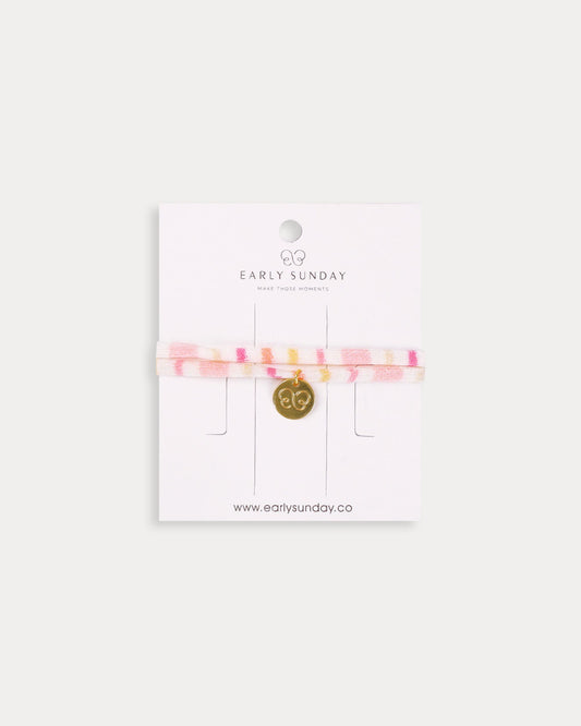 Early Sunday, Charm Bracelet in Pink Stripes print, made from Printed 70% Cotton, 30% Linen fabric, featuring a soft fabric bracelet design with a charm, shown in a front flat-lay view