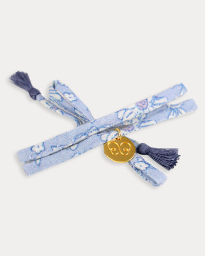 Early Sunday, Charm Bracelet in Tonal Floral Blue color, made from Printed Cotton Tiny Swiss Dobby fabric, featuring a soft fabric bracelet design with a charm, shown in an angled view with a close-up shot
