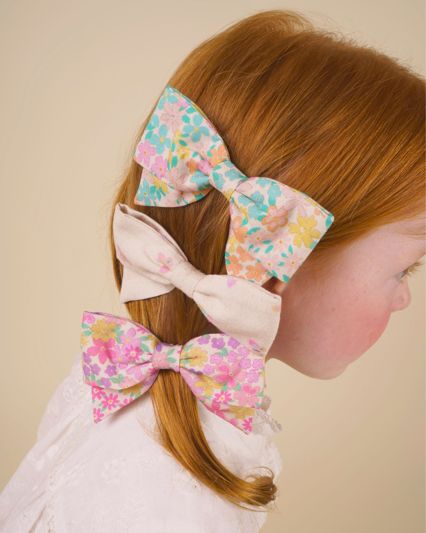 Early Sunday, Chiara Clip in Emma Floral Purple color, made from Organic Printed Cotton Cambric fabric, featuring a bow design on an alligator clip with a secure fit, shown in side view of model wearing it