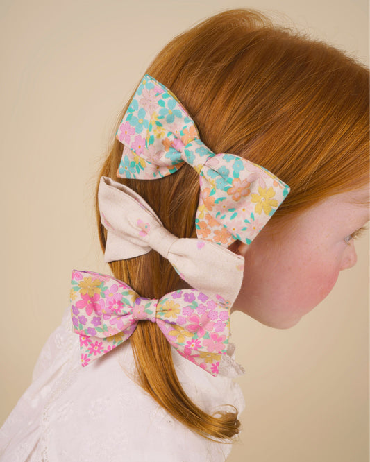 Early Sunday, Chiara Clip in Emma Floral Purple color, made from Organic Printed Cotton Cambric fabric, featuring a bow design on an alligator clip with a secure fit, shown in side view of model wearing it