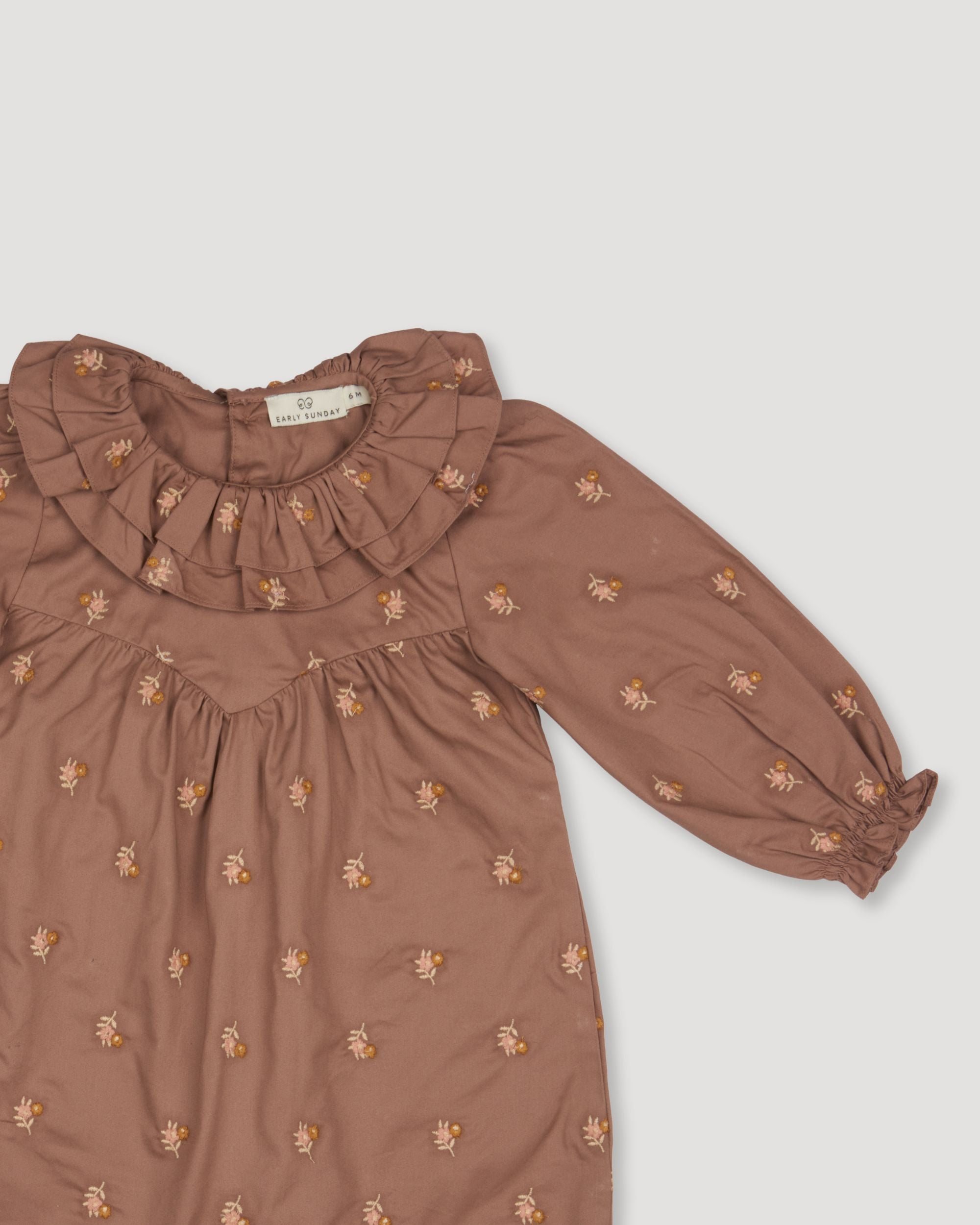 Early Sunday, Coco Baby Romper in Bark color, made from All-over Embroidered 30s Cotton Brushed Twill fabric, featuring ruffled neckline with leaf prints, shown in a closeup flat-lay view