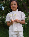 Early Sunday, Coco Blouse in Ivory color, made from all over embroidery fabric, featuring Puff sleeves, ruffled neckline and placket, shown in a front view of model wearing it