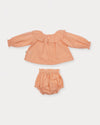 Early Sunday, Daisy Baby Blouse & Bloomer Set in Dusty Pink, made from Cotton Dobby Spot fabric, featuring a frilly neckline with detailed lace yoke & gathered sleeves, shown in a back flat-lay view