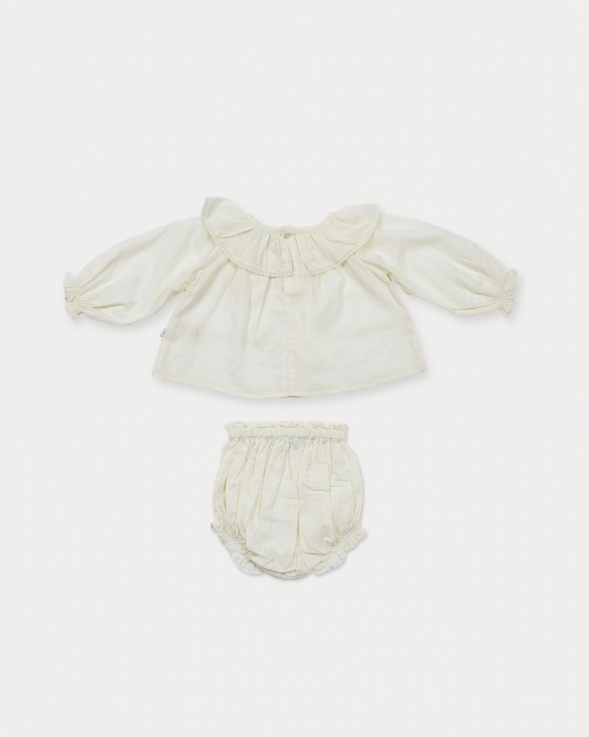 Early Sunday, Daisy Baby Blouse & Bloomer Set in Ivory, made from Cotton Dobby Spot fabric, featuring a blouse with frilly neckline & gathered sleeves, shown in a back flat-lay view